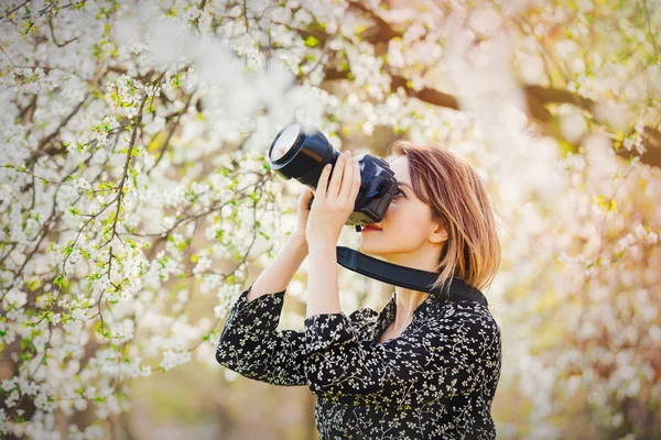 Девушка с профессиональной фотокамерой делает изображения цветка — стоковое фото