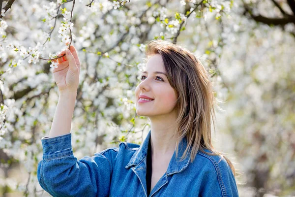 穿着粗斜纹棉布夹克的女孩呆在一棵开花的树附近 — 图库照片