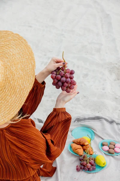 Chica sentada en la camada y sosteniendo una uva en una mano . —  Fotos de Stock