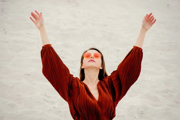 Beyaz bir kum üzerinde bir güneş gözlüğü ve bordo renkli bluz kız — Stok fotoğraf