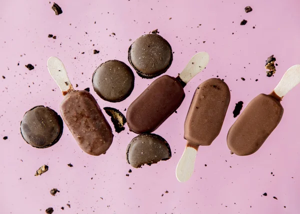 Schokoladeneis-Lollys und französische Makronen auf rosa Hintergrund. — Stockfoto