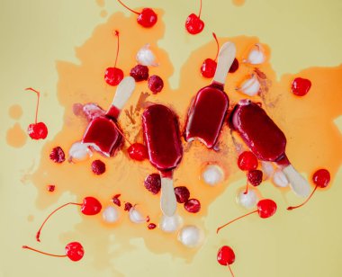 sarı arka plan üzerinde ahududu ve kiraz buz lollys