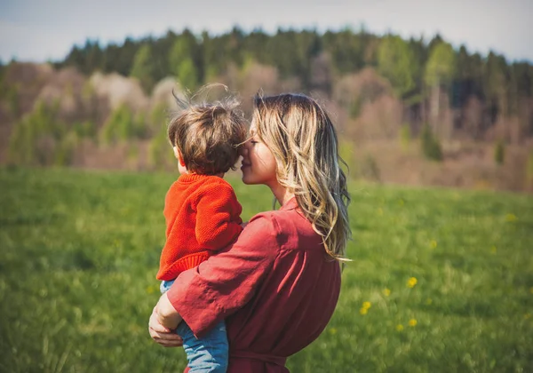 Mãe e filho no gramado do campo com montanhas e floresta — Fotografia de Stock