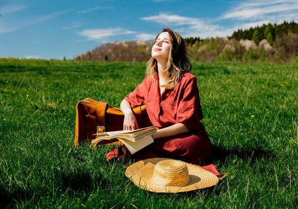 Belle fille en robe rouge et chapeau avec valise et sitti livre — Photo