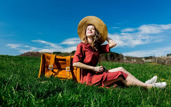 Menina bonita em vestido vermelho e chapéu sentado no prado com vinta — Fotografia de Stock