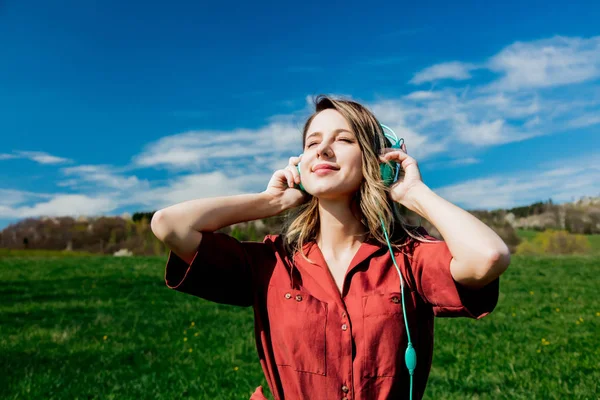 Girl in red dress and hat have a carefree time with headphones o — Stock Photo, Image