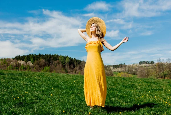 Beautiful girl in yellow dress and on mountain meadow with dande — Stock Photo, Image