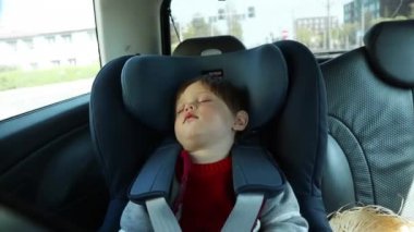Wroclaw, Poland - 20 April 2019: Little child sitting in a car chair and sleep while moving 