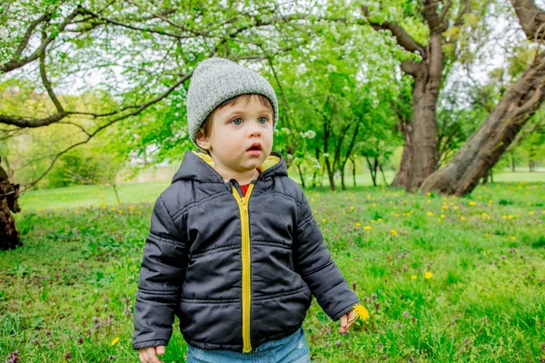 Chlapec ve svěrací kazajce a čepici v jarním časovém parku — Stock fotografie