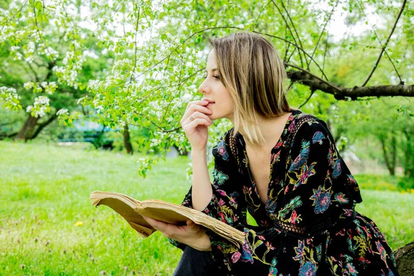 Vrouw met boek in voorjaarspark. — Stockfoto