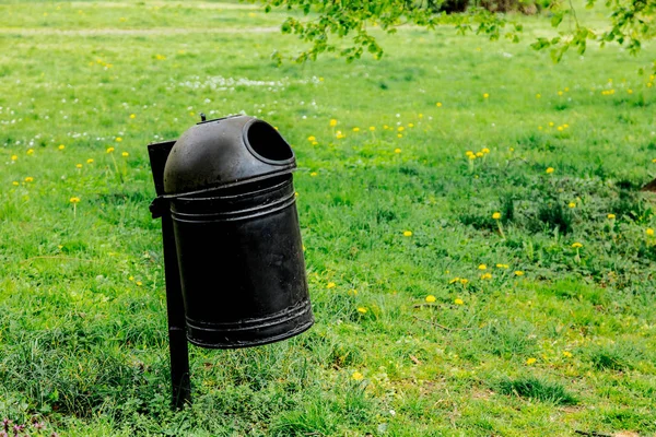 Black Metal tresh bin na zielonej trawie. — Zdjęcie stockowe