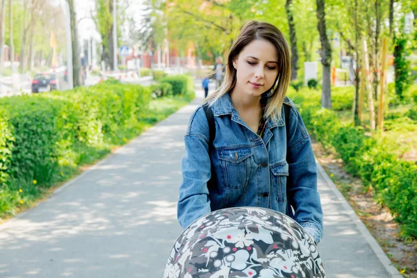 Una giovane madre con una carrozzina cammina lungo — Foto Stock