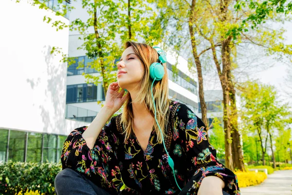 Jonge vrouw met koptelefoon in de buurt van modern gebouw van Univ — Stockfoto