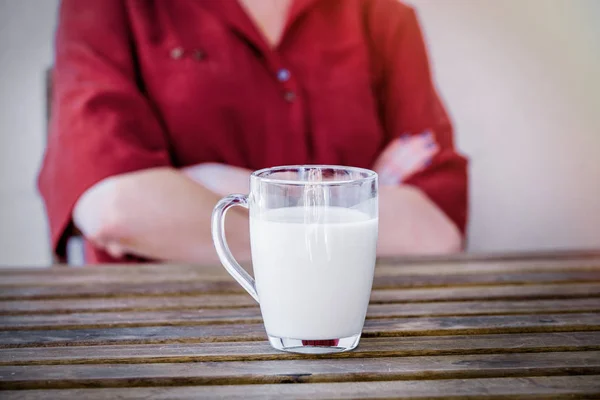 Donna triste su sfondo e vetro di latte su un tavolo su primo piano — Foto Stock