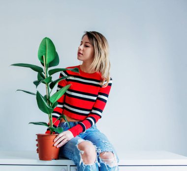 Süslü süveter ve kot pantolonlu genç bir kadın masa neasında oturuyor.