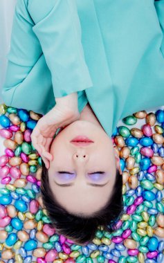 Young woman lying down on a chocolate Easter eggs.