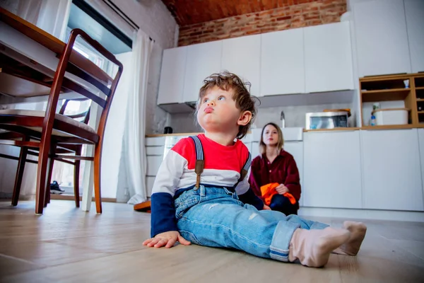 Junge überrascht auf Küchenboden sitzend — Stockfoto