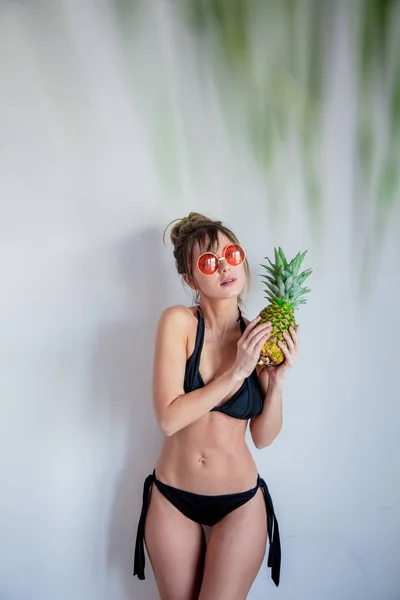 Жінка в бікіні тримає ананас і з пальмовим листям з f — стокове фото