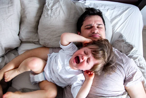 Маленький ребенок плачет на отца, когда он не хочет просыпаться — стоковое фото