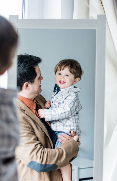 Father and sun dressing up a costume near mirror 