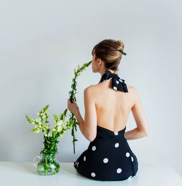 Young woman in black polka dot dress sitting on a table near Mat — 스톡 사진