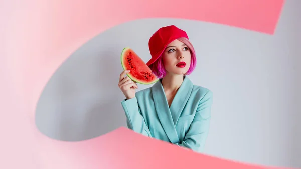 Mladá dívka s růžovými vlasy a v modré bundě drží meloun, — Stock fotografie