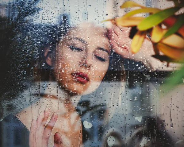 Jovem mulher triste na janela molhada após a chuva perde o plano — Fotografia de Stock