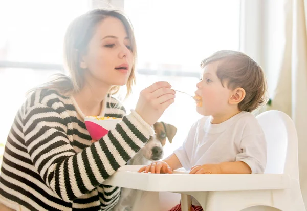 Jovem mãe tentar alimentar um menino com uma colher em um chai — Fotografia de Stock