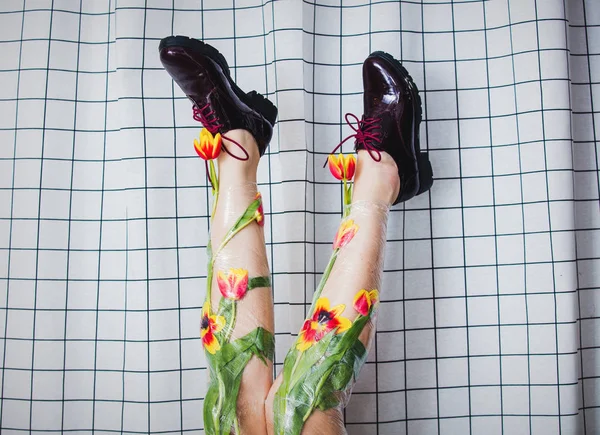 Nő tartja a lábát csomagolva celofán és tulipán flowe — Stock Fotó
