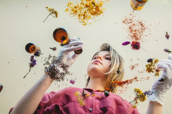 Mujer joven perfumista preparando hierbas y flores para hacer un perf —  Fotos de Stock