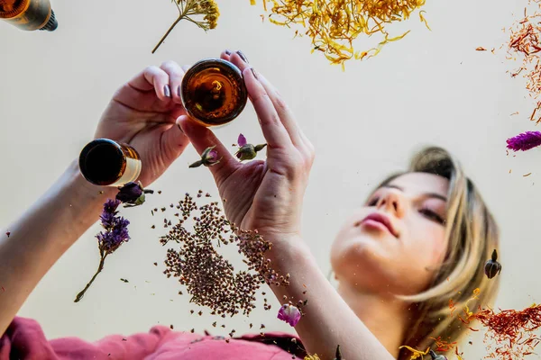 Mujer joven perfumista preparando hierbas y flores para hacer un perf —  Fotos de Stock