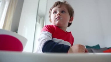 Evde beslenme sırasında bir sandalyede oturan küçük yürümeye başlayan çocuk.