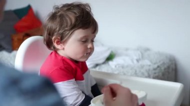 Evde beslenme sırasında bir sandalyede oturan küçük yürümeye başlayan çocuk.