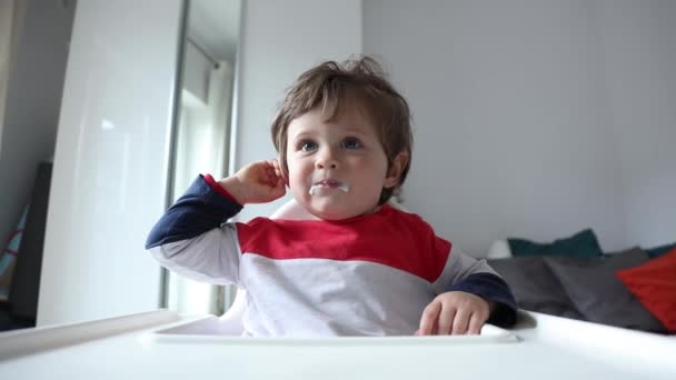 家で給餌中に椅子に座っている小さな幼児の男の子 — ストック動画