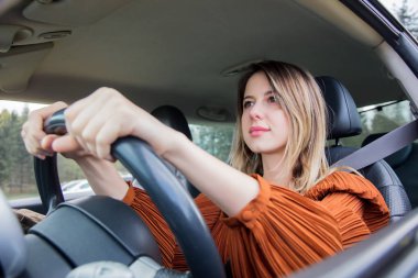 Kadın sürücü koltuğunda oturuyor ve direksiyonu tutuyor.