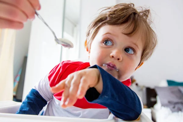 Madre nutre un piccolo bambino ragazzo con un cucchiaio durante il pranzo in t — Foto Stock