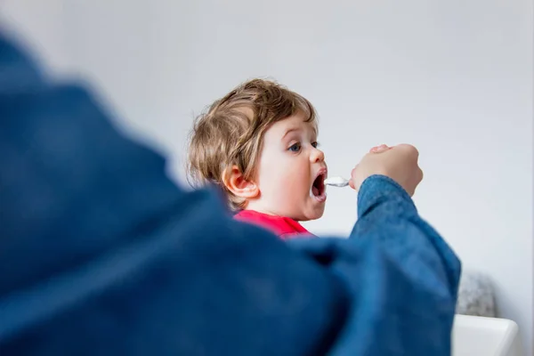 Madre nutre un piccolo bambino ragazzo con un cucchiaio durante il pranzo in t — Foto Stock