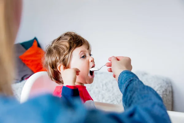 Madre nutre un piccolo bambino ragazzo con un cucchiaio durante il pranzo in t — Foto Stock