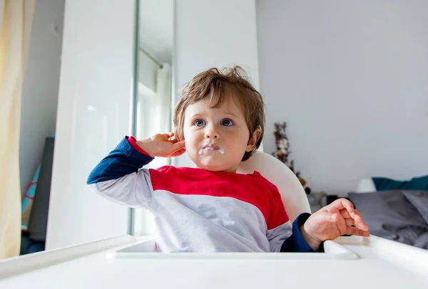 Little toddler boy sitting in a chair for feeding in a room in b — Stock Photo, Image