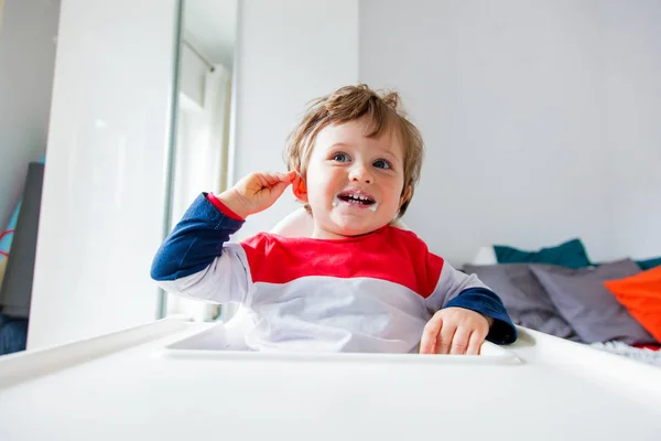 Menino pequeno sentado em uma cadeira para se alimentar em um quarto em b — Fotografia de Stock