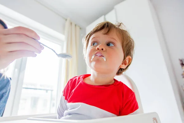 Madre nutre un piccolo bambino ragazzo con un cucchiaio durante il pranzo in t — Foto Stock