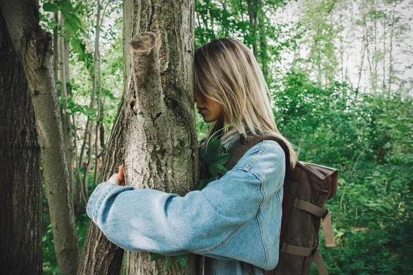 Nő hátizsákkal átölel egy fát az erdőben — Stock Fotó