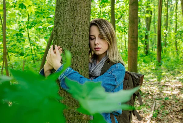 Nő hátizsákkal átölel egy fát az erdőben — Stock Fotó