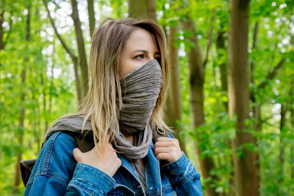 Жінка з рюкзаком ховає обличчя з шарфом у лісі — стокове фото