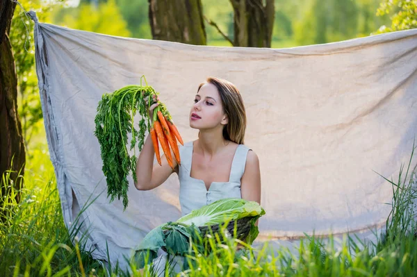 Mujer joven con verduras se sienta cerca de los árboles —  Fotos de Stock
