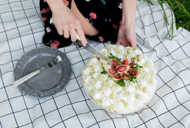 Kadın baharda açık havada kremalı turta kesti.