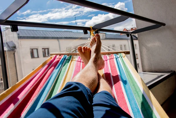 Legs of a man lying on a hammock on a balcony in the city — Stock Photo, Image