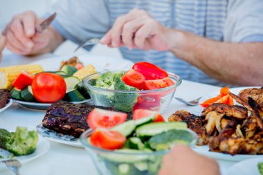 masada oturan ve ızgara tavuk kanatları ve vegatebles yeme insanlar 