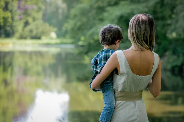 Mère tient son fils sur une main près de la rivière — Photo