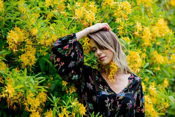 Donna di stile vicino a fiori gialli in un grarden in tempo di primavera — Foto Stock